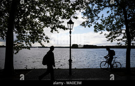 Berlin, Deutschland. 16 Aug, 2019. Ein Mann und eine Radfahrer kann auf die Greenwich Promenade an der Tegeler See gesehen werden. Credit: Christoph Soeder/dpa/Alamy leben Nachrichten Stockfoto