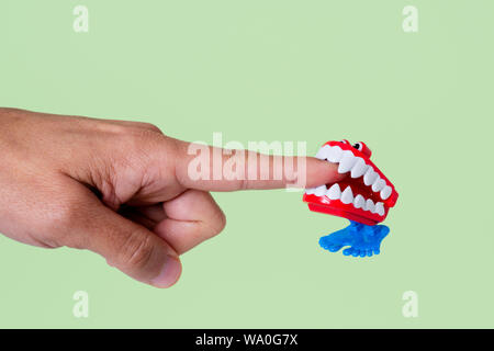 Eine lustige Gebiss Beißen der Zeigefinger von einem jungen Mann auf einem grünen Hintergrund, mit einigen leeren Raum um Stockfoto