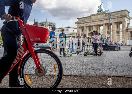 Mann mit Vermietung e-Bike von Uber, Elektroroller, Elektroscooter, Elektroroller, vor dem Brandenburger Tor in Berlin. Stockfoto