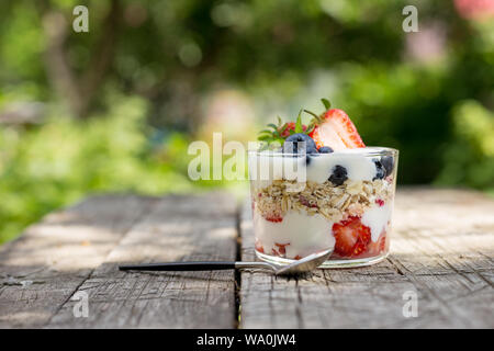 Freien Speicherplatz mit Müsli mit Joghurt und Erdbeeren und Blaubeeren in Glas auf Holz- Hintergrund Stockfoto