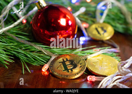 Weihnachtsdekor Bitcoins, Kugel auf einem Holzbrett mit Kiefernzweigen und Urlaub. Münzen bitcoin unter dem Zweig von einem Weihnachtsbaum, auf der Boa Stockfoto