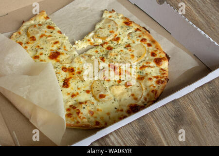 Käse Pizza mit Birnen im Karton Aufenthalt auf Holztisch. Close up Perspektive betrachten. Eine Scheibe oder ein Stück fehlt. Mahlzeit ist auf weißem Küche papier Stockfoto