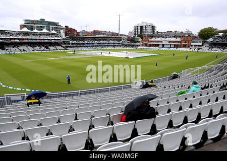 Zuschauer Unterschlupf vor dem Regen als Spiel wird durch schlechtes Wetter in Tag drei der Asche Test Match auf Lord's, London verzögert. Stockfoto