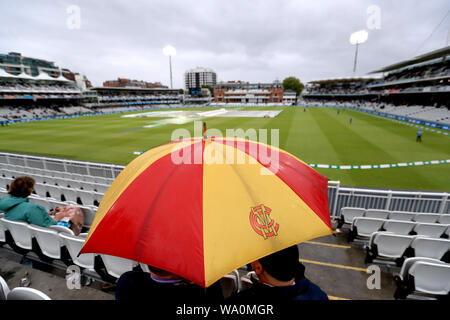 Zuschauer Unterschlupf vor dem Regen als Spiel wird durch schlechtes Wetter in Tag drei der Asche Test Match auf Lord's, London verzögert. Stockfoto
