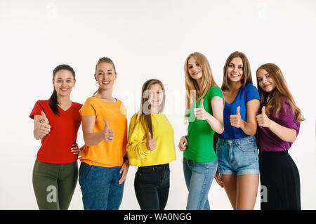 Junge Frauen getragen in LGBT Flagge Farben auf weißem Hintergrund. Kaukasische weibliche Modelle in hellen Hemden. Glücklich aus, Daumen nach oben. Vertrauen LGBT pride, Menschenrechte, Freiheit der Wahl Konzept. Stockfoto