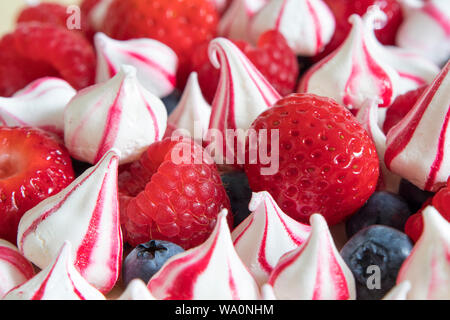 Leckeren Käsekuchen gekrönt mit Baiser, frisch Himbeeren, Erdbeeren und Blaubeeren. Stockfoto