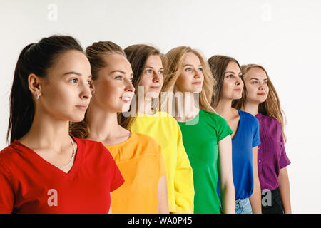 Junge Frauen getragen in LGBT Flagge Farben auf weißem Hintergrund. Kaukasische weibliche Modelle in hellen Hemden. Fröhlich, lächelnd. Vertrauen LGBT pride, Menschenrechte, Freiheit der Wahl Konzept. Stockfoto