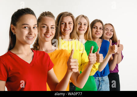 Junge Frauen getragen in LGBT Flagge Farben auf weißem Hintergrund. Kaukasische weibliche Modelle in hellen Hemden. Glücklich aus, Daumen nach oben. Vertrauen LGBT pride, Menschenrechte, Freiheit der Wahl Konzept. Stockfoto