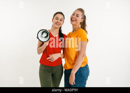 Junge Frauen getragen in LGBT Flagge Farben auf weißem Hintergrund. Kaukasische Modelle in hellen Hemden. Glücklich aus, lächelte und umarmte. LGBT pride, der Menschenrechte und der Wahl Konzept. Holding Mundstück. Stockfoto