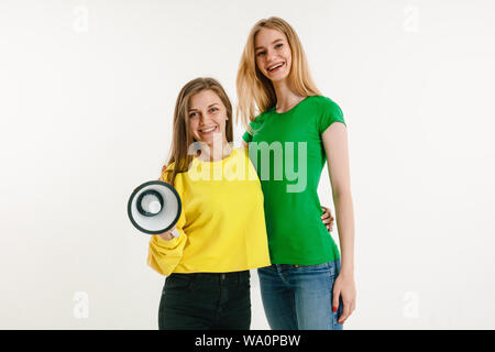 Junge Frauen getragen in LGBT Flagge Farben auf weißem Hintergrund. Kaukasische Modelle in hellen Hemden. Glücklich aus, lächelte und umarmte. LGBT pride, der Menschenrechte und der Wahl Konzept. Holding Mundstück. Stockfoto