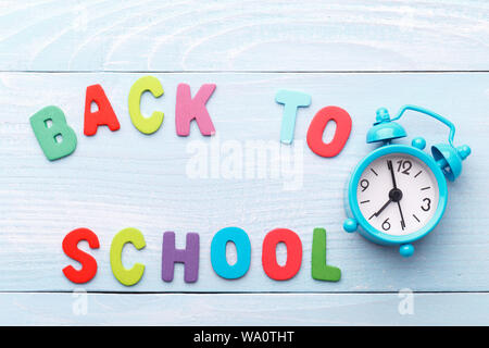 Zurück zum Konzept der Schule, mit bunten Holz- buchstaben und Wecker auf Blau Holz- Hintergrund Stockfoto