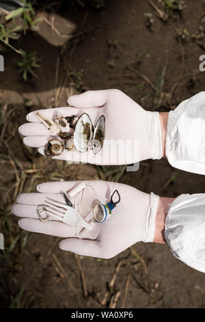 7/8-Ansicht von Ökologen in Latex Handschuhe holding Muscheln und plastik Müll Stockfoto