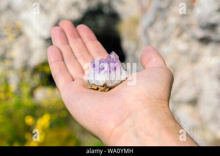 Druse von natürlichen unbehandelt violette Kristalle Amethyst auf ein Stück Felsen liegt auf der Hand Stockfoto