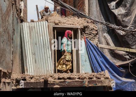 Frauen bei Gebäuden, die durch ein Erdbeben in Kathmandu beschädigt. Stockfoto