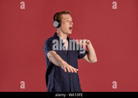 Nahaufnahme Porträt einer jungen hübschen Ingwer Fellow in einem stilvollen Navy t-shirt Hören von Musik über Kopfhörer, singen und tanzen, während p Stockfoto