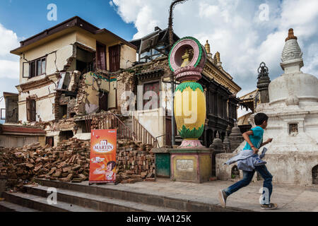 Ein Junge läuft hinter einem Gebäude schlecht durch ein Erdbeben in Kathmandu, 2015 beschädigt. Stockfoto