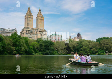 New York Central Park, Ansicht im Sommer von Menschen Ruderboote am Central Park See mit dem San Remo Gebäude im Hintergrund, Manhattan, NYC, USA Stockfoto