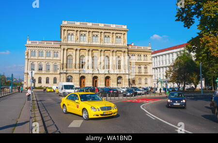 Gebäude der Ungarischen Akademie der Wissenschaften mit einem gelben Taxi verlassen den Parkplatz. Budapest, Ungarn Stockfoto