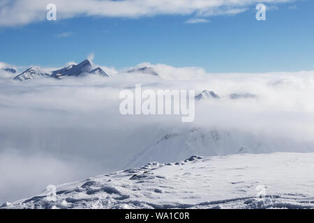 Schneebedeckten Hang und lichtdurchfluteten Berge unter Wolken am schönen, sonnigen Tag. Kaukasus Berge im Winter, Georgien, Region Gudauri. Sicht auf Kudebi montieren. Stockfoto