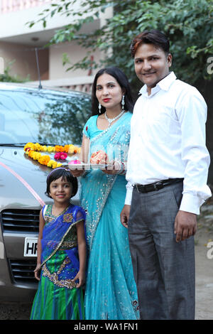 Familie stand vor einem Auto mit Pooja thali Stockfoto