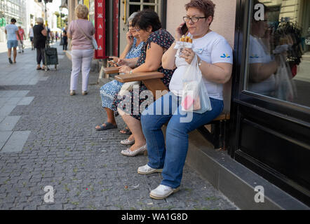 Belgrad, Serbien, 26. Juli 2019: städtische Szene mit Frau sitzt auf der Bank vor einer Bäckerei und einen Snack Stockfoto