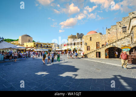 Touristen Sehenswürdigkeiten besichtigen, einkaufen und speisen Sie in der historischen Hippokrates Platz, im Zentrum der Altstadt der Insel Rhodos, Griechenland. Stockfoto