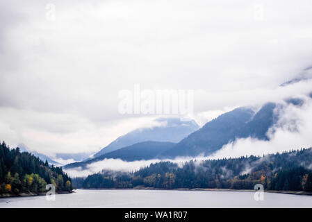 Nebel und Wolken bewaldete Berge in der Nähe von Lake in British Columbia, Kanada. Stockfoto