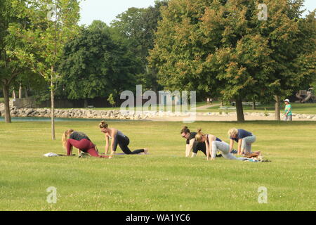 Kleine yoga Klasse für die Gemeinschaft an einem warmen August Morgen am Ufer des Lake Michigan. Stockfoto