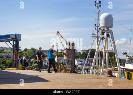 8. August 2019 Shore crew Landung ein Fang von Krebsen aus einem kleinen Schiff an Ardglass Hafen auf einem hellen, sonnigen Nachmittag Stockfoto