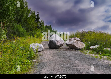 Stein Steine blockieren die Forststraße Sommer Landschaft. Auf einem waldweg ist ein großer Felsen, versperrt den Weg. Stockfoto