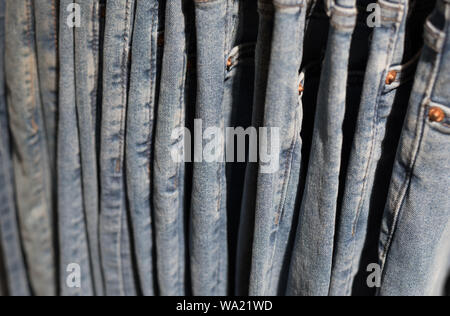 Jeans hängen an einem shop Rack, eine Seitenansicht, eine Nahaufnahme. Denim Background, verschwommen (geringe Tiefenschärfe). Stockfoto