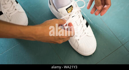 Bangkok, Thailand - 20. Mai 2019: ein Mann Schnürsenkel weiss Adidas Superstar Sneaker. Stockfoto
