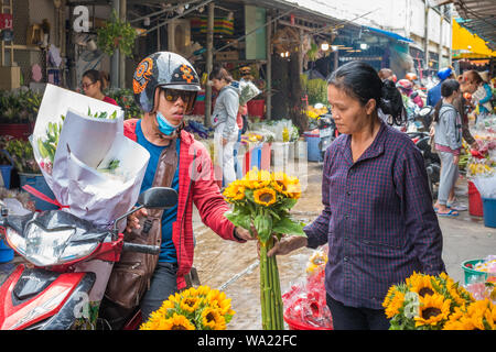 Ho Chi Minh City, Vietnam - 12. April 2019: eine Frau auf dem Motorrad kauft einen Strauß Blumen von einem Verkäufer bei Ho Thi Ky Blumenmarkt. Stockfoto