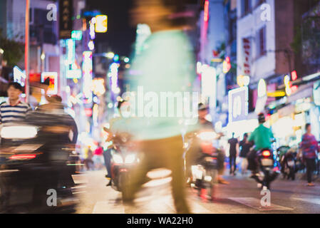 Defokussierten blurry Szene in der Nacht Straße mit verschwommenen Motorrad Verkehr, Fußgänger, Tafeln und alle Arten von Neonlicht - Ho Chi Minh City Stockfoto