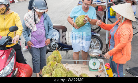 Ho Chi Minh City, Vietnam - Mai 1, 2019: Ein Mann kauft ein Durian bei einem Straßenhändler auf einem Straßenmarkt neben Cho Lon-bus station. Stockfoto