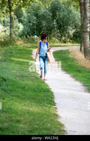 In Scherben spaziert wirkende Seniorin in einem Weg Stockfoto