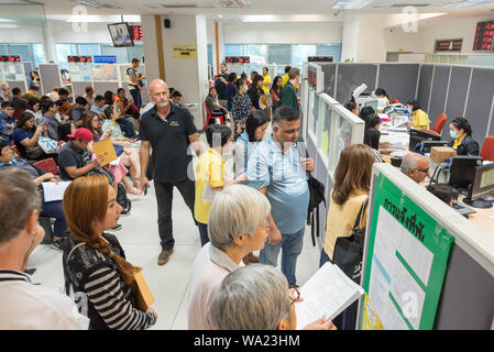 Bangkok - Juli 11, 2019: Ausländer und Thais warten, bis sie an der Reihe sind für die Anmeldung des Wohnsitzes in überfüllten Thailand beantragen. Stockfoto