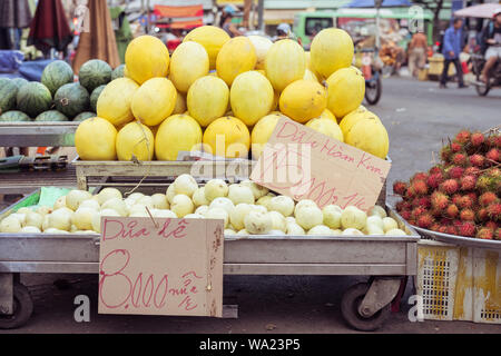 Melonen auf Ständen mit Preis tags: goldene Melone, 15.000 Dong (0,6 $) für 1 kg, Melone und Birne, 8.000 Dong für ein Stück. Markt in Cho Lon, Ho Chi Minh Stockfoto