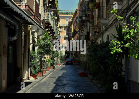 Typische italienische Straße in Catania. Gepflasterte Straße mit wenig Bäumen und bunten Gebäude mit kleinen Balkonen auf beiden Seiten Stockfoto