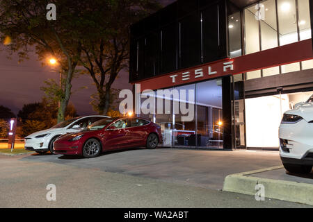 Eingang von Tesla Showroom und Service Center mit neuen Fahrzeugen, geparkt, front, spät in der Nacht. Stockfoto