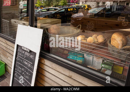 Ein Bild durch die Bäckerei Fenster. In Weidenkörbe one's hat Brot und Brötchen. Stockfoto