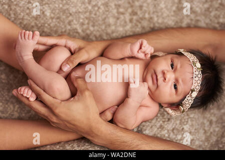 Eltern umarmt Baby liegend auf weiches Bett Stockfoto