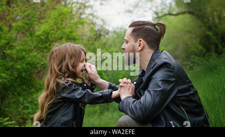 Modernes, stilvolles Familie Fuß in den Park. Vati ergriff das Kind bei der Nase. Sie sind Aprilscherze. Akt die Made. Zeit zusammen. Familie suchen. Urb. Stockfoto