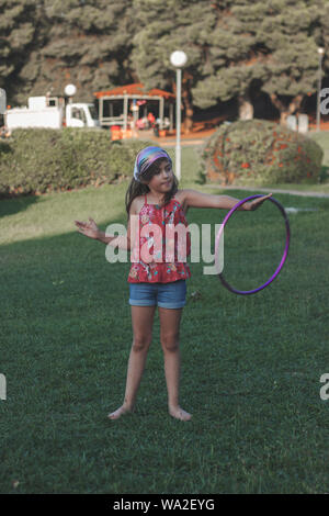 Kleines Mädchen ist das Spielen mit Ihrem Hula Hoop im Park Stockfoto