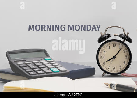 Wecker mit Notebook, Taschenrechner, Stift und Tasse Kaffee auf grauem Hintergrund auf die Tabelle Stockfoto
