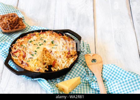 Schwäbische Spätzle mit geschmolzenem Käse und gebratenen Zwiebeln auf einem blauen Handtuch für die Küche und eine weiße Holztisch. Oktoberfest Gericht. Deutsche traditionelle Mahlzeit. Stockfoto