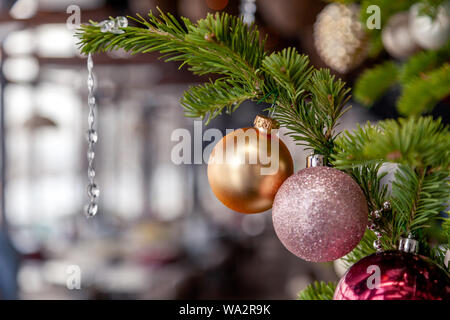 Nahaufnahme Weihnachten Neujahr Dekoration, Tannenzweigen mit glänzenden festlichen Spielzeug golden und rosa Kugeln auf dem Hintergrund der inneren Veranda moderne rest Fichte Stockfoto