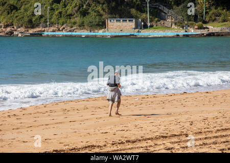 Im mittleren Alter älterer Mann Übungen durch Joggen entlang Palm Beach in Sydney, Australien Stockfoto