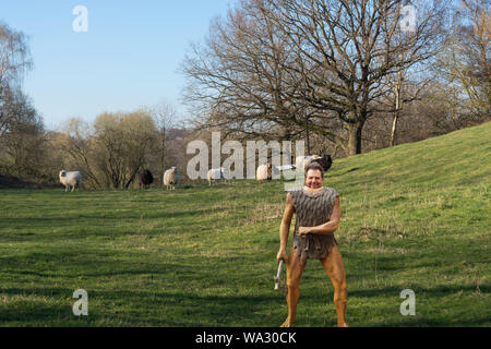 Cartoon Illustration eines Neandertalers Abbildung aus Kunststoff mit Beil auf einer Wiese während der Jagd für Schafe Stockfoto