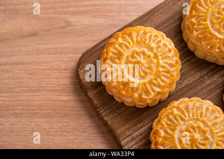 Runde frisch gebackene Mond kuchen Gebäck - Chinesische moonckae für Mid-Autumn Moon Festival auf hölzernen Hintergrund und Serviertablett, Ansicht von oben, flach. Stockfoto